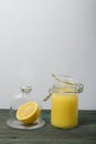 Lemon Kurd in a glass jar. Nearby is half a lemon in a container with a glass lid. Stand on brushed boards, on a white background Royalty Free Stock Photo