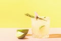 Lemon lemonade drink in elegant glasses on a bright pastel colored background. Bright sunshine. Summer concept.