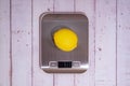 An lemon lies on a digital kitchen scale on a table of light boards Royalty Free Stock Photo