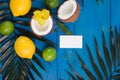 Lemon, lime, coconut and palm leaves and business card on blue background Royalty Free Stock Photo