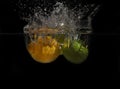 Lemon and lime splashing into the water on a black background Royalty Free Stock Photo
