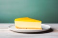 Lemon or mango cheesecake slice with yellow glaze, on a white plate against minimal teal background with copy space