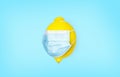 Lemon with a medical mask on a blue background. Vitamins for colds. Coronavirus protection concept. Infection and prevention.