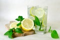 Lemon mint detox water. Home-made lemonade with mint, lemon and ice in glasses. Wooden board, sliced lemon and mint leaves Royalty Free Stock Photo