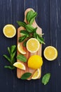 Lemon and mint leaves served on wooden kitchen board on black rustic table, ingredient for summer cocktails and lemonade Royalty Free Stock Photo