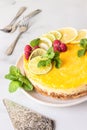 Lemon mousse vanilla cheesecake with lemon curd decorated by lemon and lime slices, frozen raspberry and mint. Royalty Free Stock Photo