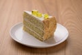 Lemon multi layered cake decorated with citron jelly and mint served on white plate on wooden background. Royalty Free Stock Photo