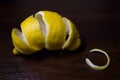 Lemon peel or lemon twist on a dark brown wooden background. Close up Royalty Free Stock Photo