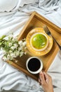 Lemon Pistachio Donut with cup of coffee, fork and flowers served in plate on wooden tray top view of baked breakfast