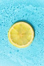 Lemon slice on blue carbonated water background in bright sunlight Royalty Free Stock Photo