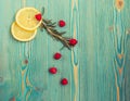 Lemon slices, raspberry and rosemary on turquoise wooden desk