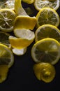 Lemon slices and whole lemon peel curled in a spiral on a glittery black glass background Royalty Free Stock Photo