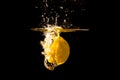 A lemon splashes into water in black background