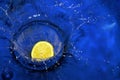 Lemon splashing blue water