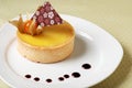 Lemon tart decorated and drops of orange sauce