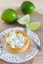 Lemon tart pie on white plate spoone on sackcloth with fresh lime Royalty Free Stock Photo