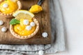 Lemon tartlets. Homemade shortbread mini tarts with lemon curd and meringue on wooden board, light background Royalty Free Stock Photo