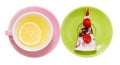 Lemon tea with a whole slice of lemon in a pink cup, next to a piece of strawberry cake on a green saucer, close-up on a white Royalty Free Stock Photo