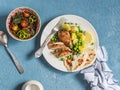 Lemon thyme baked chicken, boiled potatoes with green peas, salad with lentils and tomatoes on a blue background.