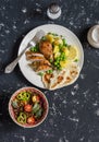 Lemon thyme baked chicken, boiled potatoes with green peas, salad with lentils and tomatoes on a dark background.