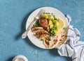 Lemon thyme baked chicken, potatoes and green peas on a white plate on a blue background. Royalty Free Stock Photo