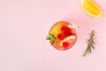 Lemon water or lemonade with raspberry and rosemary on a pink background