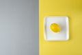 Lemon on a white plate on a gray and yellow background. Trending color of year 2021 Illuminating and Ultimate gray. Top view