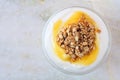 Lemon yogurt with granola, overhead view on white marble