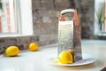 Lemon and lemon zest with metal grater on the white plate standing on the kitchen table. Yellow and gray trendy colors Royalty Free Stock Photo