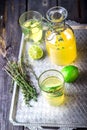Lemonade in bottle and two glasses on vintage metal tray. Wooden background.