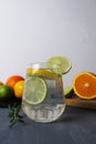 lemonade citrus orange lime lemon in a glass with ice and rosemary on a gray background next to the fruits close-up. Preparation Royalty Free Stock Photo