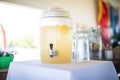 lemonade in a clear dispenser with a spigot at a party