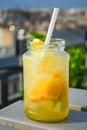 Lemonade cocktail with lemon in glass jar, cold refreshing drink or beverage with ice at a rooftop bar. Royalty Free Stock Photo