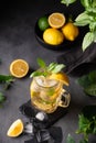 Lemonade drink with fresh lemon, lime, mint and ice in a jar. Refreshing citrus mojito cocktail or cold tea on a dark background. Royalty Free Stock Photo