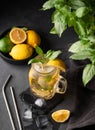 Lemonade drink with fresh lemon, lime, mint and ice in a jar. Refreshing citrus mojito cocktail or cold tea on a dark background. Royalty Free Stock Photo