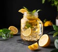 Lemonade drink with fresh lemon, mint and ice in a jar. Refreshing citrus mojito cocktail or cold tea on a dark background. Royalty Free Stock Photo