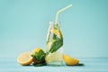 Lemonade drink of soda water, lemon and mint in jar on turquoise background