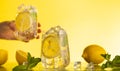 Lemonade with fresh slice lemon and mint leaves. Woman holding glass of lemonade. Summer homemade drink