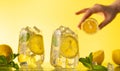 Lemonade with fresh slice lemon and mint leaves. Woman holding half of lemon. Summer homemade drink