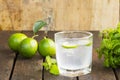 Lemonade in glass and green lemon on wooden background.Drink for health.Close up Royalty Free Stock Photo