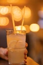 Lemonade in a glass with ice cubes on chopped lemon wedges. Refreshing cold drink with two straws on the table in a human hand Royalty Free Stock Photo