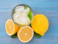 Lemonade in a glass, a lemon half, fresh leaves on the blue wood Royalty Free Stock Photo