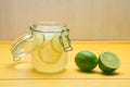 Lemonade with ice, lemon and lime in a jar on a yellow wooden ba Royalty Free Stock Photo