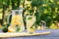 Lemonade in jug and glass and lemon with lime on wooden table