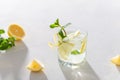 Lemonade with lemon, mint and ice cubes in glass on white stone background. Cold summer refreshing drink or beverage. Summer Menu Royalty Free Stock Photo