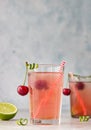 Lemonade or non-alcohol cocktail with cherry and lime in glass on grey background. Summer berry drink Royalty Free Stock Photo