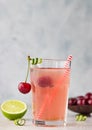 Lemonade or non-alcohol cocktail with cherry and lime in glass on grey stone background. Summer berry drink Royalty Free Stock Photo