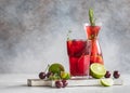 Lemonade or non-alcohol cocktail with cherry and lime, grey concrete background. Summer refreshment drink Royalty Free Stock Photo