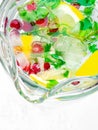 Lemonade pitcher with lemon slices, mint leaves, red berries and ice cubes, glass jug. View with copy space Royalty Free Stock Photo