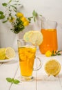 Lemonade in a tall glass with ice, a slice of lemon and mint on a white wooden background. Summer cool drink Royalty Free Stock Photo